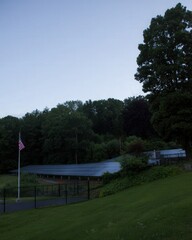 American flag waves proudly in the foreground of a rural solar farm at sunrise, clean energy panels stretching into the glowing horizon.
