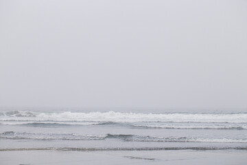 Ocean Waves Crashing into the Sand on the Beach in the Early Morning Fog