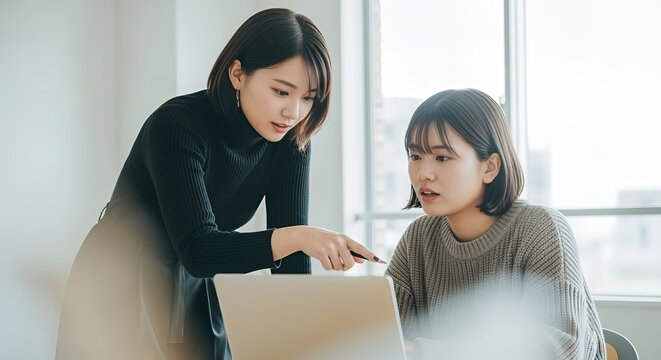 パソコンを使い後輩に教える女性社員