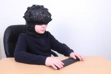 Young adult works on a laptop wearing a sleek noninvasive brain computer interface headset in a minimalist office, calm focus on device and face.