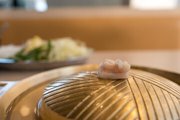 Close up of cubes lard meats on gold metallic brass BBQ pan on the electric stove. Thai buffet food...