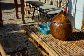 A traditional iced tea container and glasses on a bamboo table at a rustic cafe in rural Vietnam....