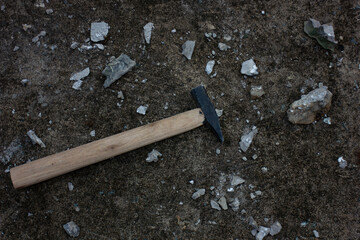 A geologist's hammer lying on the ground among broken rock fragments. An image for construction,...