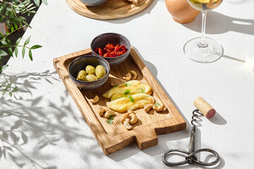 Halloumi with olives and sundried tomatoes, bright sunlight, overhead minimalistic wood serving