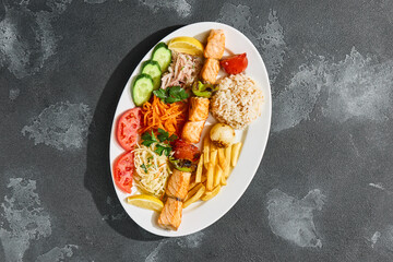 Trout shashlik plate with grilled vegetables, rice and fries, bright overhead composition