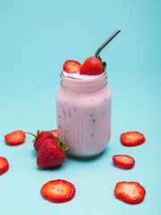 A mason jar brimming with a cool strawberry drink, garnished with fresh strawberries and metal straw