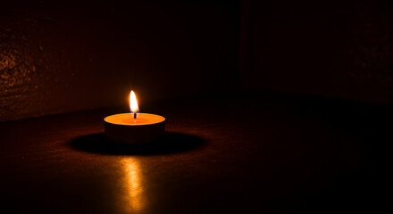 Single candle flame illuminates darkness, representing hope and solitude
