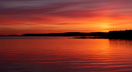 Fototapeta premium Vibrant Sunset Reflection over Tranquil Waters, an Atmospheric Finnish Landscape