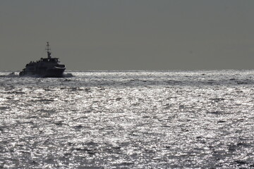 Scenic Cruise Boat Tour at Cliffs of Moher, Ireland – Silhouetted Vessel Sailing Across Sparkling Atlantic Ocean Waters Under Soft Evening Light, Wild Atlantic Way Adventure Travel Scene