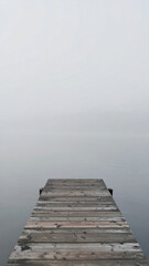 Fototapeta premium Wallpaper of Wooden Dock At Lake With Misty Background