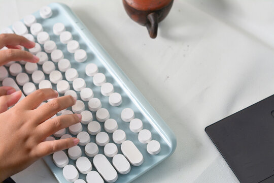 Child's hands typing on a modern retro-style keyboard. Creative tech scene with vintage elements and a clean, minimalist workspace
