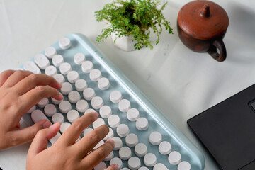 Child's hands typing on a modern retro-style keyboard. Creative tech scene with vintage elements and a clean, minimalist workspace