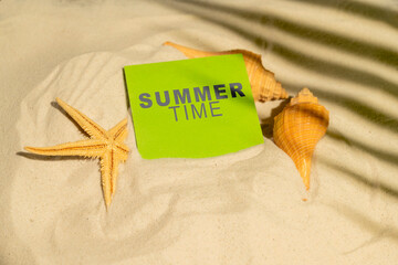 Starfish and seashells with a text of Summer time in the note on a beautiful sandy beach. Natural...
