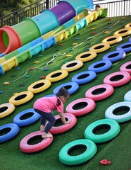 Young Girl Climbing on Colorful Playground Tire Obstacle Course Outdoors