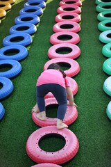 Young Girl Climbing on Colorful Playground Tire Obstacle Course Outdoors