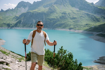 Hiker walking by turquoise mountain lake on sunny day