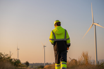 Engineer man working with tablet at windmill farm Generating electricity clean energy. Wind turbine...