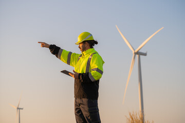 Engineer man working with tablet at windmill farm Generating electricity clean energy. Wind turbine...