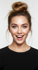 Woman with blonde hair in messy high top knot bun with face framing pieces on gray background. Casual updo hairstyle with loose strands for wedding styling