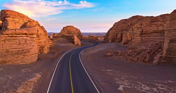 Aerial view of spectacular Yardang landform mountain and asphalt road landscape at sunrise in Xinjiang, China.