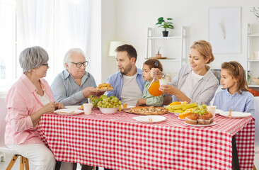 Family gathers at home for a holiday, enjoying dinner, lively conversation and fun around the table. The celebration is filled with food eating, laughter, and a warm, happy atmosphere.
