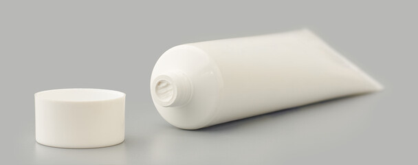 opened toothpaste tube with white cap isolated gray background, mock-up template of glue, cream, gel or shampoo, blank package or medicine or cosmetics concept, soft focus