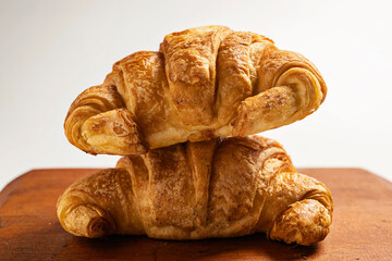 Freshly baked croissants on a wooden tray isolated over a white background