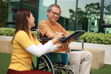 Obraz premium Help support retirement health care. A man is being cared for privately at home by an Asian woman who has Alzheimer's and is being closely monitored.