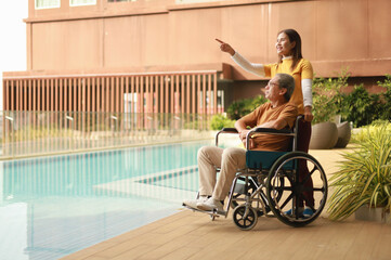 Obraz premium Help support retirement health care. A man is being cared for privately at home by an Asian woman who has Alzheimer's and is being closely monitored.