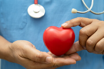 Asian woman doctor holding red heart for health in hospital.