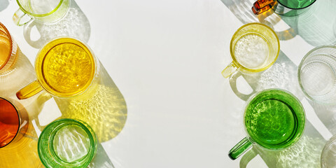 Vibrant of colorful glass cups on white, banner, casting artistic light reflections and shadows in...