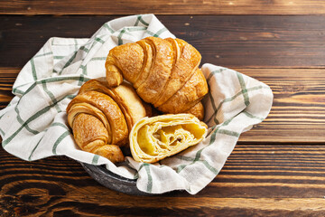 Slices of freshly baked croissants on a napkin with a wooden background. Top view