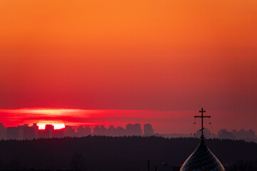 A stunning sunset casts orange hues on the skyline, silhouetting a church spire