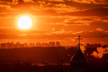Golden rays illuminate the horizon, creating a stunning backdrop against a church dome
