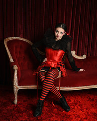 Burlesque circus performer, fantasy female model in gothic halloween jester clown costume with top...