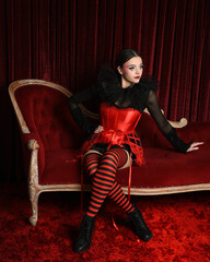 Burlesque circus performer, fantasy female model in gothic halloween jester clown costume with top...
