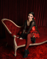 Burlesque circus performer, fantasy female model in gothic halloween jester clown costume with top...