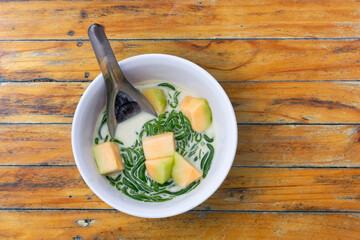 Lod Chong dessert with cantaloupe in coconut milk, beautifully presented on a rustic wooden table