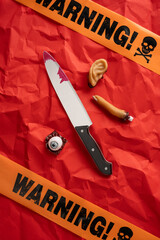 Scary Halloween vertical concept featuring a blood-smeared knife, creepy props, and warning tape on...