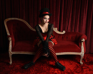 Burlesque circus performer, fantasy female model in gothic halloween jester clown costume with top...