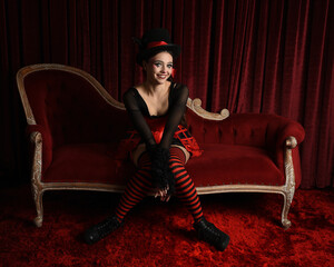 Burlesque circus performer, fantasy female model in gothic halloween jester clown costume with top...