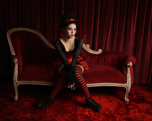 Burlesque circus performer, fantasy female model in gothic halloween jester clown costume with top...