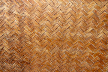 Texture of a woven wooden covering with a diagonal pattern in brown tones.