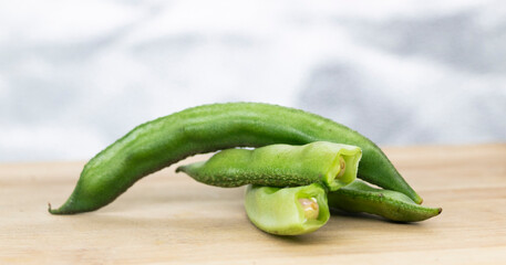 Close up of a wooden crate filled with broad beans,the green bean pods background,,