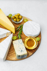 Cheese platter with assorted cheeses, olives, and honey on wooden board