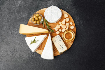 Cheese and olive platter arranged on a wooden board with fresh herbs