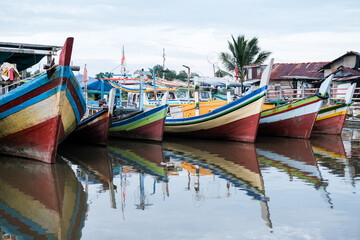 Traditional Indonesian wooden fishing boats rest quietly on calm river waters, their vivid colors reflecting a rich maritime heritage.