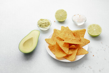 Nachos with avocado, guacamole, lime and salt on white table