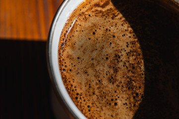  Close-up of fresh coffee with rich crema in a mug on a rustic wooden table. Warm, inviting natural...