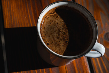  Close-up of fresh coffee with rich crema in a mug on a rustic wooden table. Warm, inviting natural...